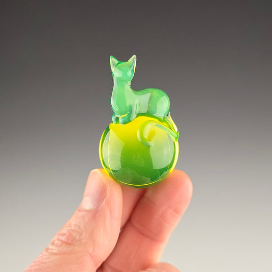 Green uv cat loafing on a uv reactive glass marble in the color of uranium glass