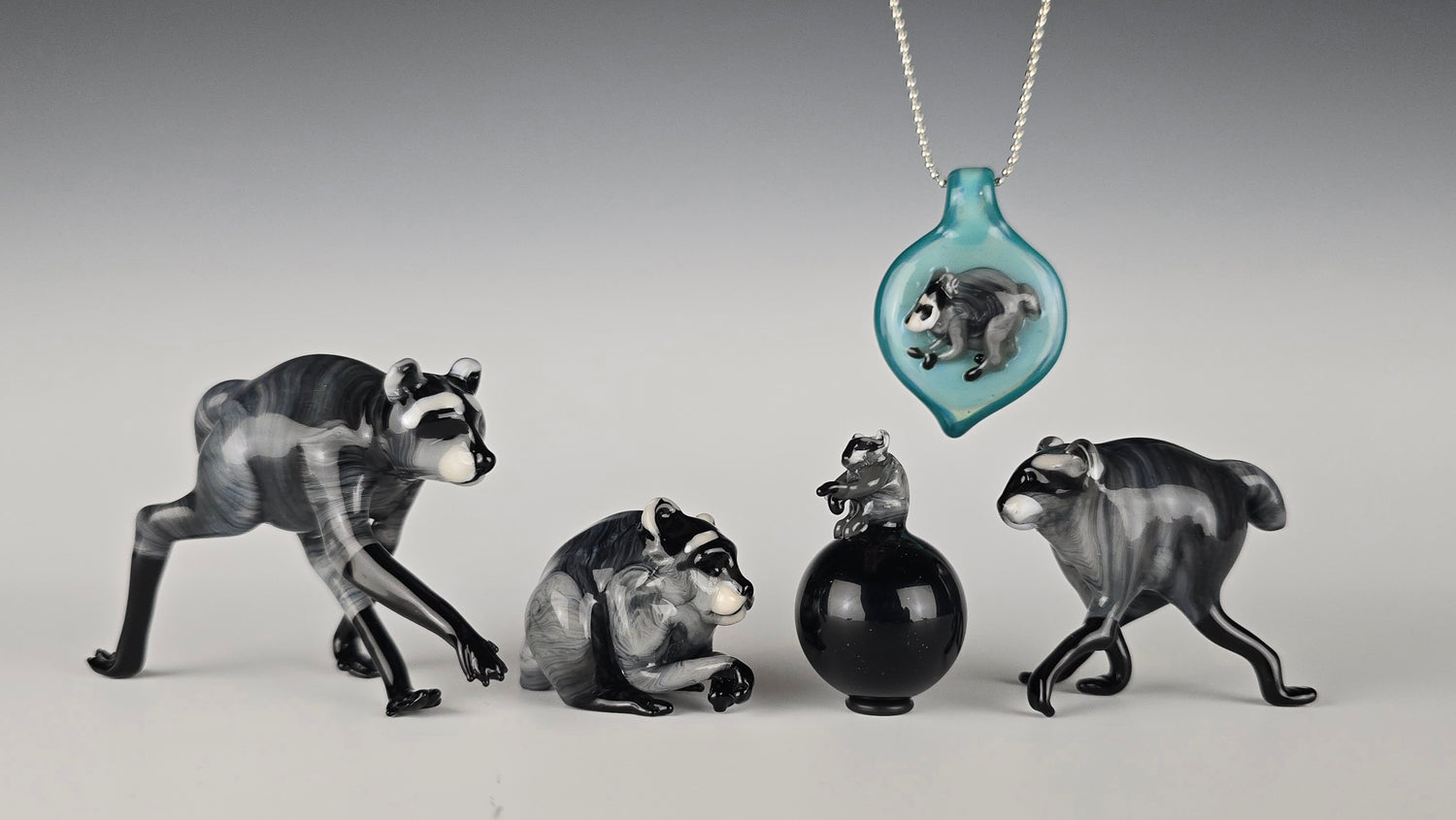 Small sculptures of Jimothy the Raccoon made of glass.