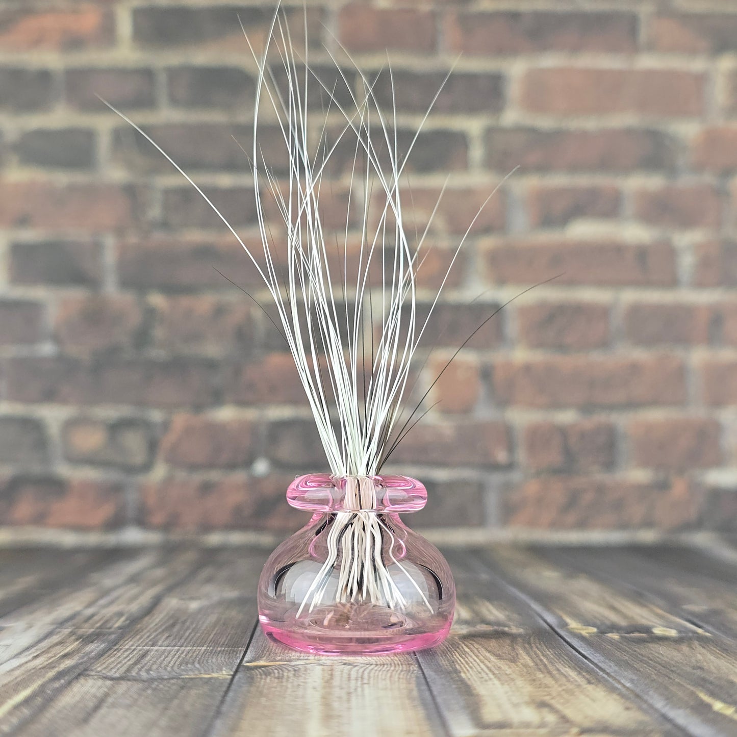 Miniature hand blown pink glass vase filled with found fallen cat whiskers