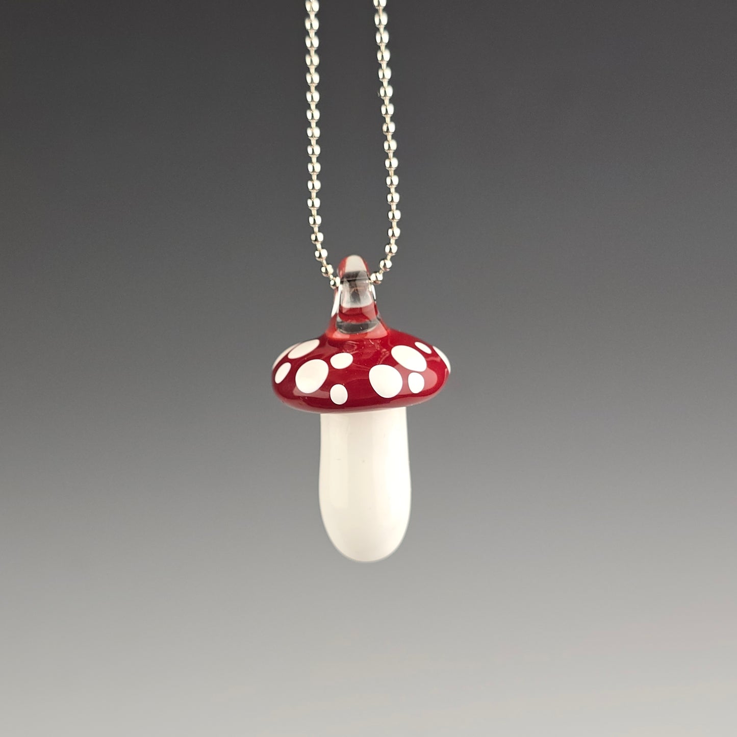 Mushroom-shaped pendant on a chain against a gray background