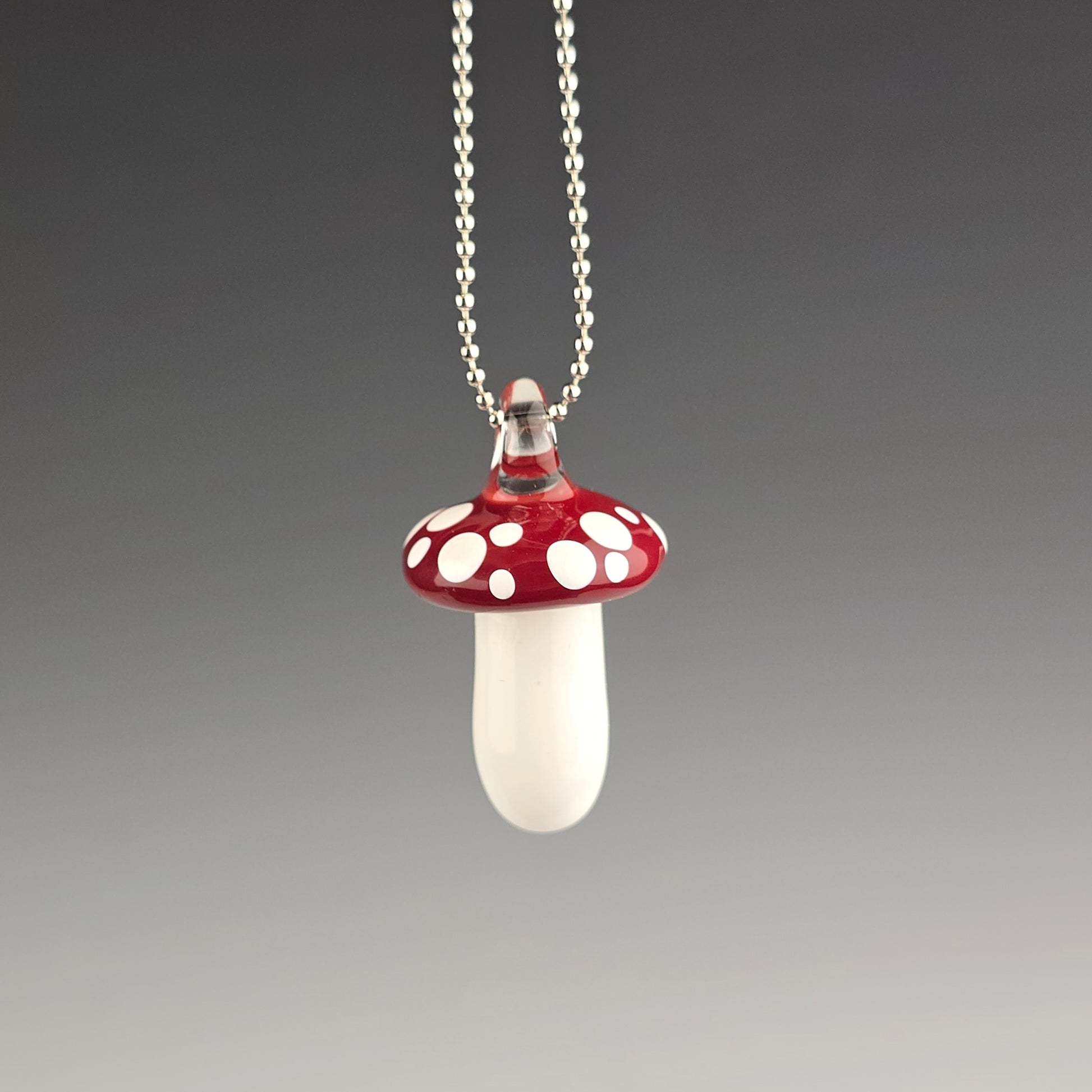 Mushroom-shaped pendant on a chain against a gray background