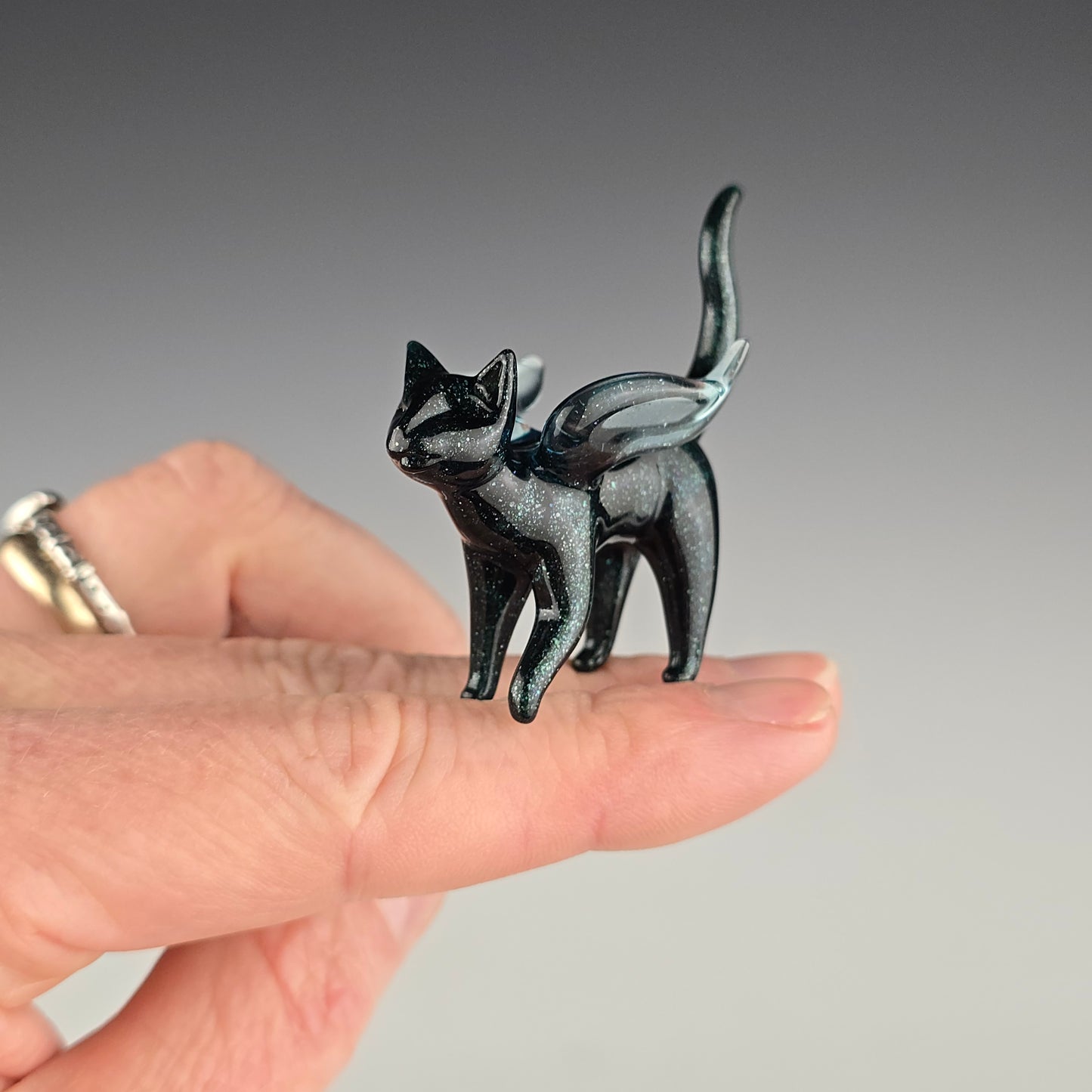 Small memorial sculpture of a winged cat made out of sparkly blue glass