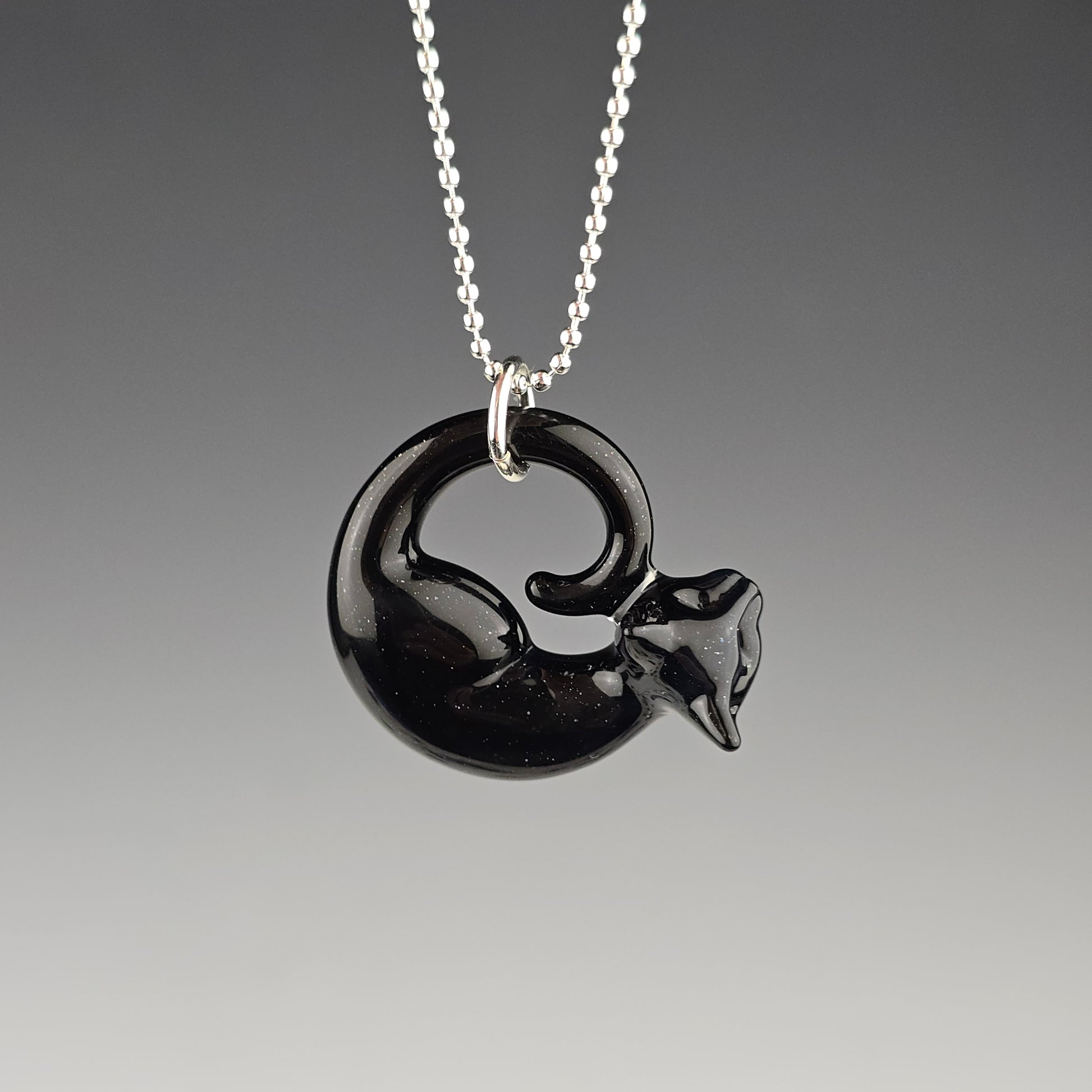 small sparkly black sleeping cat sculpture that is worn as a necklace