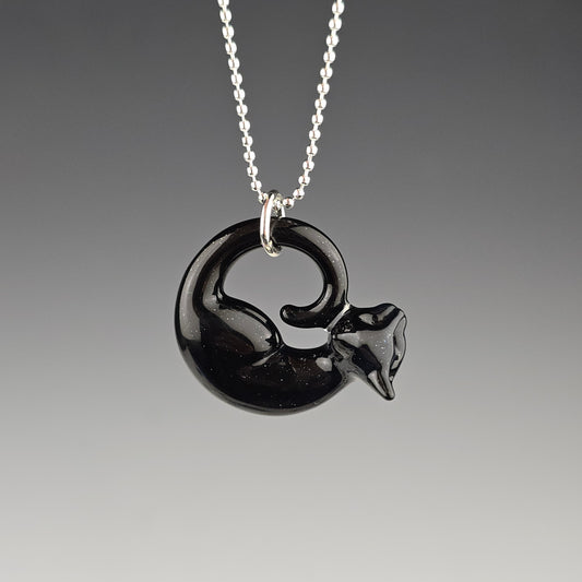 small sparkly black sleeping cat sculpture that is worn as a necklace