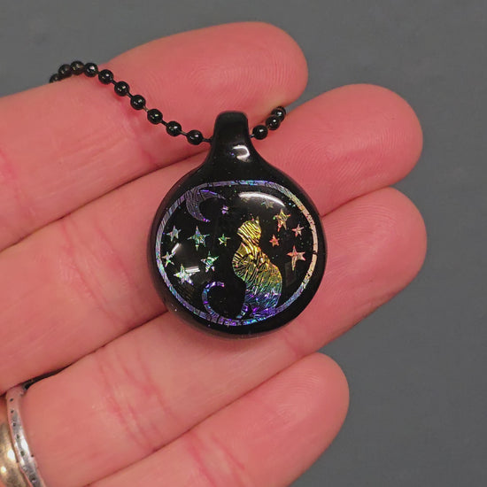Video of a Rainbow Dichro image pendant of a Cat under a crescent moon and starry sky.